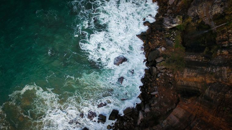 Aerial view of a cliff edge and breaking surf photographed from a drone