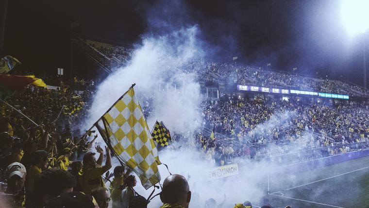 Home end with flags and smoke