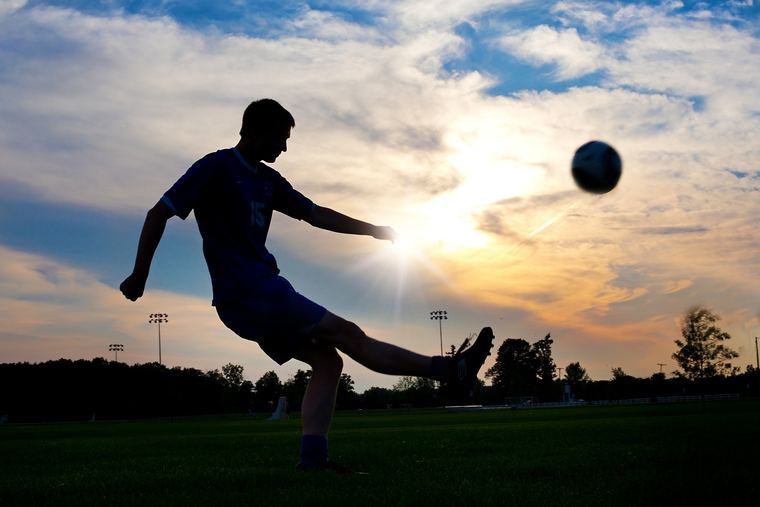 Player striking the ball into low evening sun