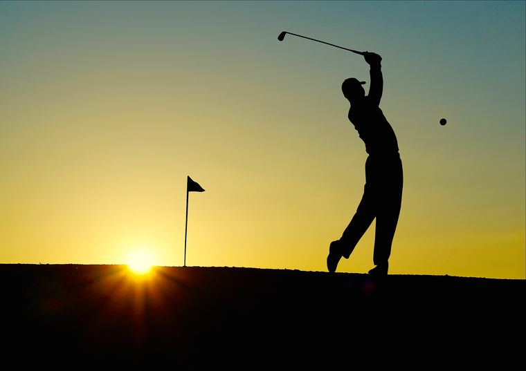 Golfer silhouetted at the top of the backswing
